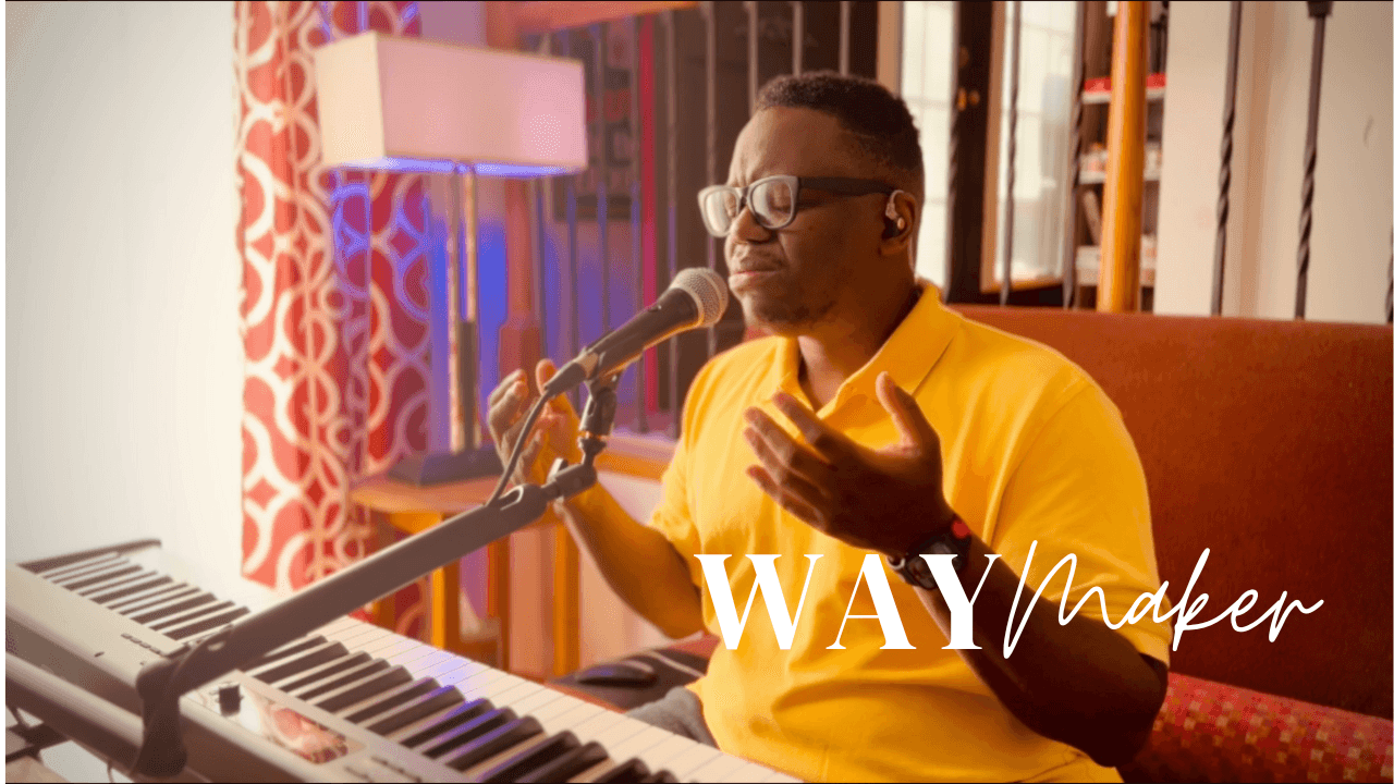 Person in yellow shirt singing into a microphone beside a keyboard with 'Way Maker' text overlay.