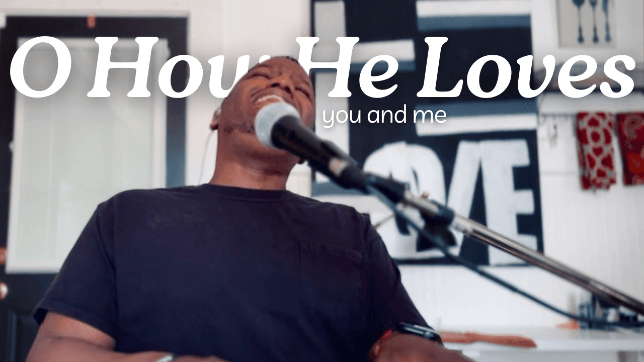 Person singing into a microphone with text overlay 'Oh How He Loves you and me'