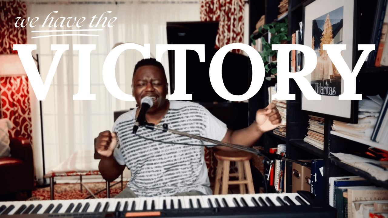 Man singing at keyboard with microphone, text overlay 'we have the VICTORY'.